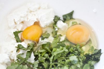 Смешайте сыр, мяту, яйца и петрушку.
Добавьте в смесь лук и шпинат.  Тщательно перемешайте. 