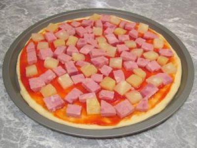 Смажьте его томатным соусом (или пастой). Выложите кусочки ветчины и ананаса.