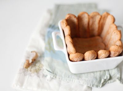 Форму смажьте маслом. Выложите форму (http://www.edasla.ru/recipe/1205) бисквитами (дно и стенки), обмакивая их в сироп очень быстро.