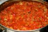 Добавить измельченный перчик чили, перемешать овощи. Добавить томат-пасту, соль и сахар. Перемешать овощную смесь и поставить икру на огонь.