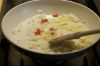 Обжарить лук на сковороде с растительным маслом пока он не станет прозрачным, после чего добавить перец. Жарить лук с перцем около 5 минут. 