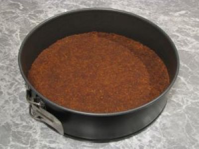 В форму для выпечки сложите печенье с маслом. Слой должен получится плотный. Уберите на час в холодильник.