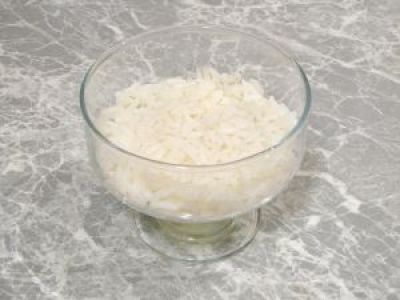 Рис промойте в холодной воде и отварите. Выложите на дно креманки и смажьте майонезом.