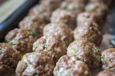 В фарш добавить приправы по вкусу, половину измельчённого чеснока, соль, сформировать фрикадельки, поставить в разогретую духовку на 20 минут.