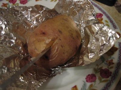 Выньте форму из духовки, дайте картофелю слегка остыть, разрежьте каждый клубень пополам и ложкой извлеките мякоть.