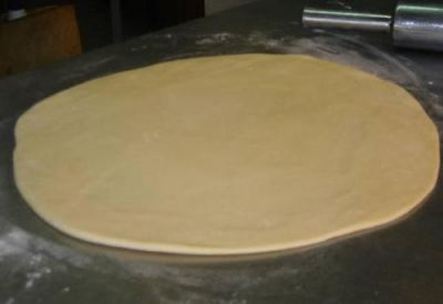 Присыпьте поверхность стола мукой, выложите тесто и раскатайте его до толщины около 3 мм.