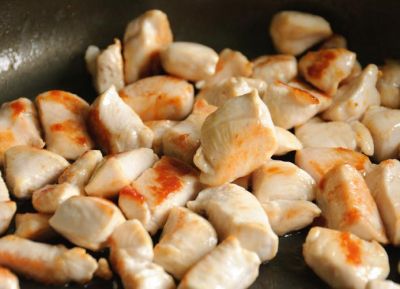 Далее выкладываем в сковородку куриные кусочки, перемешиваем с овощами. Жарим смесь 3-5 минут на сильном огне. Постоянно мешаем, чтобы не сгорели морковь с луком.