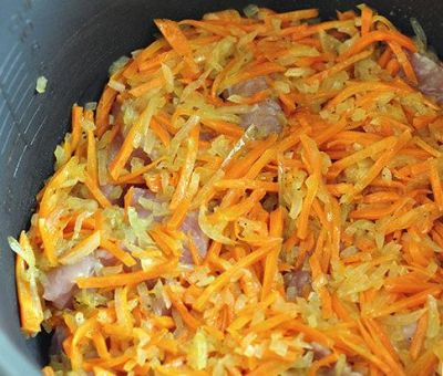 Мелко нарезать репчатый лук. Натереть на крупной терке морковь.
Выложить репчатый лук к обжаренному мясу. Добавить морковь и томатный соус краснодарский и  продолжать жарить еще 5 мин. Добавить 700 мл. кипяченной воды,и готовить до конца программы "Жарка".