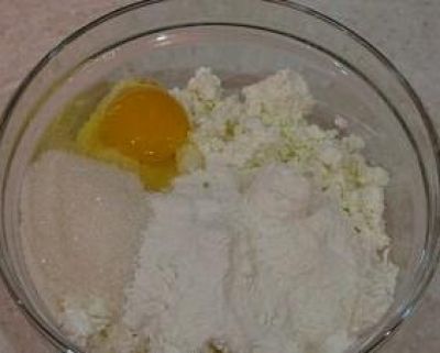 Творог протереть через сито и перемешать с яйцом, сахаром, просеянной мукой и разрыхлителем.