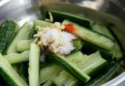 Огурцы немного отжимаем и сливаем сок. На них кучкой выкладываем красный острый перец, кориандр, выдавленный чеснок и сахар.
