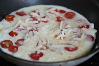 Яичную массу влейте в сковороду, накройте крышку и убавьте огонь. 