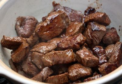 Обжаренное мясо выложите в кастрюлю или глубокую сковороду с толстыми стенками, присолите.